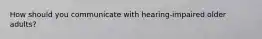 How should you communicate with hearing-impaired older adults?