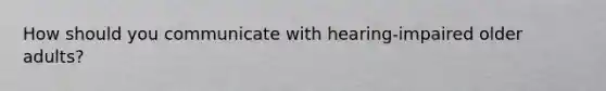How should you communicate with hearing-impaired older adults?