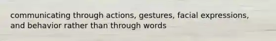 communicating through actions, gestures, facial expressions, and behavior rather than through words