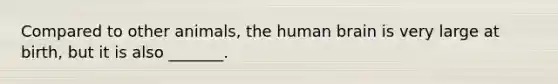 Compared to other animals, the human brain is very large at birth, but it is also _______.