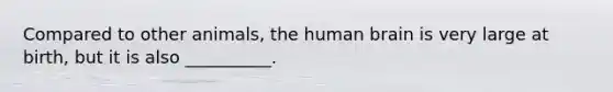 Compared to other animals, the human brain is very large at birth, but it is also __________.