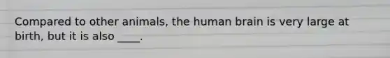 Compared to other animals, the human brain is very large at birth, but it is also ____.