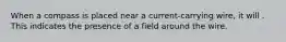 When a compass is placed near a current-carrying wire, it will . This indicates the presence of a field around the wire.