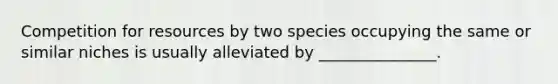 Competition for resources by two species occupying the same or similar niches is usually alleviated by _______________.