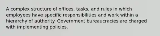 A complex structure of offices, tasks, and rules in which employees have specific responsibilities and work within a hierarchy of authority. Government bureaucracies are charged with implementing policies.