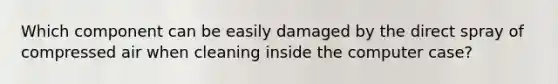 Which component can be easily damaged by the direct spray of compressed air when cleaning inside the computer case?