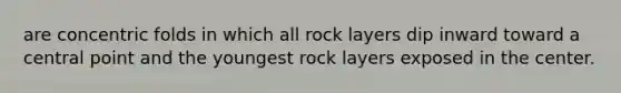 are concentric folds in which all rock layers dip inward toward a central point and the youngest rock layers exposed in the center.