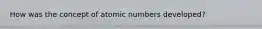 How was the concept of atomic numbers developed?