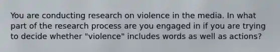 You are conducting research on violence in the media. In what part of the research process are you engaged in if you are trying to decide whether "violence" includes words as well as actions?