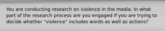 You are conducting research on violence in the media. In what part of the research process are you engaged if you are trying to decide whether "violence" includes words as well as actions?