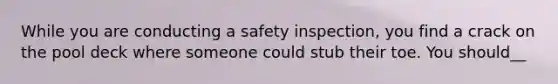 While you are conducting a safety inspection, you find a crack on the pool deck where someone could stub their toe. You should__