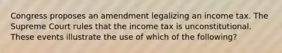 Congress proposes an amendment legalizing an income tax. The Supreme Court rules that the income tax is unconstitutional. These events illustrate the use of which of the following?