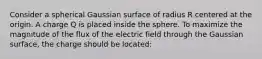 Consider a spherical Gaussian surface of radius R centered at the origin. A charge Q is placed inside the sphere. To maximize the magnitude of the flux of the electric field through the Gaussian surface, the charge should be located: