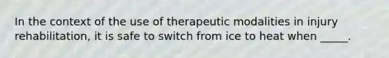 In the context of the use of therapeutic modalities in injury rehabilitation, it is safe to switch from ice to heat when _____.