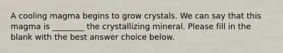 A cooling magma begins to grow crystals. We can say that this magma is ________ the crystallizing mineral. Please fill in the blank with the best answer choice below.