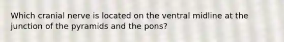 Which cranial nerve is located on the ventral midline at the junction of the pyramids and the pons?