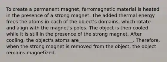 To create a permanent magnet, ferromagnetic material is heated in the presence of a strong magnet. The added thermal energy frees the atoms in each of the object's domains, which rotate and align with the magnet's poles. The object is then cooled while it is still in the presence of the strong magnet. After cooling, the object's atoms are_______________________. Therefore, when the strong magnet is removed from the object, the object remains magnetized.