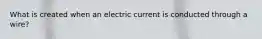 What is created when an electric current is conducted through a wire?