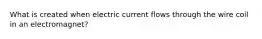 What is created when electric current flows through the wire coil in an electromagnet?