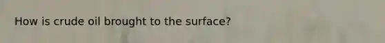 How is crude oil brought to the surface?