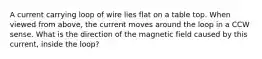 A current carrying loop of wire lies flat on a table top. When viewed from above, the current moves around the loop in a CCW sense. What is the direction of the magnetic field caused by this current, inside the loop?