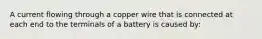 A current flowing through a copper wire that is connected at each end to the terminals of a battery is caused by: