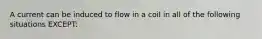 A current can be induced to flow in a coil in all of the following situations EXCEPT: