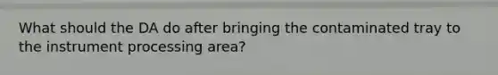 What should the DA do after bringing the contaminated tray to the instrument processing area?