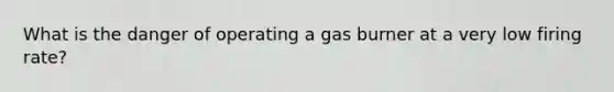 What is the danger of operating a gas burner at a very low firing rate?