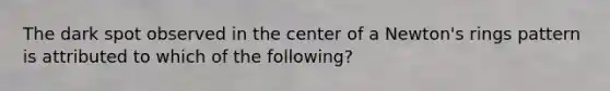 The dark spot observed in the center of a Newton's rings pattern is attributed to which of the following?