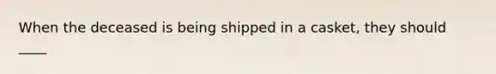 When the deceased is being shipped in a casket, they should ____