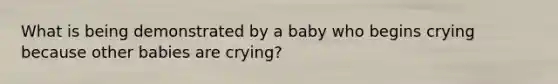 What is being demonstrated by a baby who begins crying because other babies are crying?