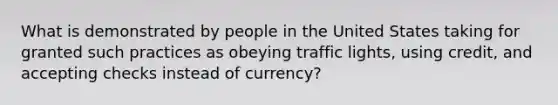 What is demonstrated by people in the United States taking for granted such practices as obeying traffic lights, using credit, and accepting checks instead of currency?