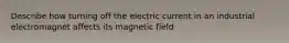 Describe how turning off the electric current in an industrial electromagnet affects its magnetic field