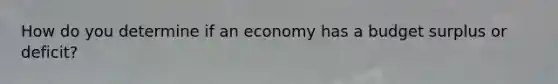 How do you determine if an economy has a budget surplus or deficit?