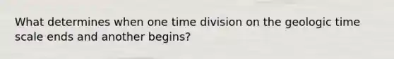 What determines when one time division on the <a href='https://www.questionai.com/knowledge/k8JpI6wldh-geologic-time' class='anchor-knowledge'>geologic time</a> scale ends and another begins?