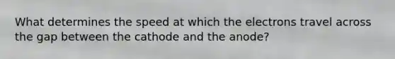 What determines the speed at which the electrons travel across the gap between the cathode and the anode?