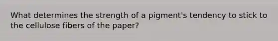 What determines the strength of a pigment's tendency to stick to the cellulose fibers of the paper?