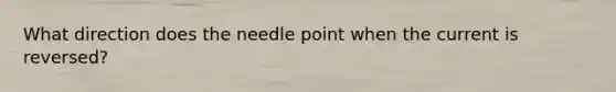 What direction does the needle point when the current is reversed?