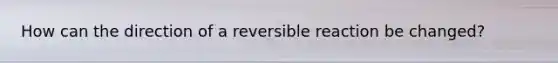 How can the direction of a reversible reaction be changed?