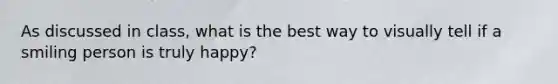 As discussed in class, what is the best way to visually tell if a smiling person is truly happy?