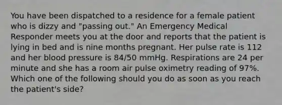 You have been dispatched to a residence for a female patient who is dizzy and​ "passing out." An Emergency Medical Responder meets you at the door and reports that the patient is lying in bed and is nine months pregnant. Her pulse rate is 112 and her blood pressure is​ 84/50 mmHg. Respirations are 24 per minute and she has a room air pulse oximetry reading of​ 97%. Which one of the following should you do as soon as you reach the​ patient's side?