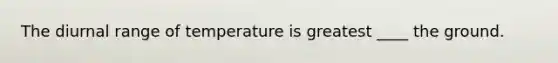 The diurnal range of temperature is greatest ____ the ground.