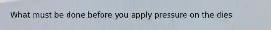 What must be done before you apply pressure on the dies