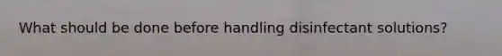 What should be done before handling disinfectant solutions?