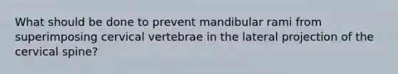 What should be done to prevent mandibular rami from superimposing cervical vertebrae in the lateral projection of the cervical spine?