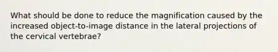 What should be done to reduce the magnification caused by the increased object-to-image distance in the lateral projections of the cervical vertebrae?