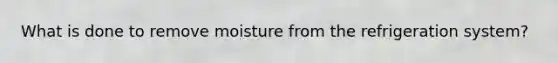 What is done to remove moisture from the refrigeration system?