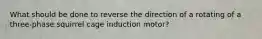 What should be done to reverse the direction of a rotating of a three-phase squirrel cage induction motor?