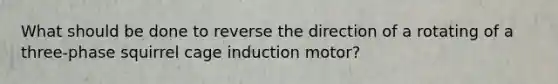 What should be done to reverse the direction of a rotating of a three-phase squirrel cage induction motor?